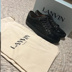 Svarta sneakers från Lanvin - Lanvin sneakers i svart skinn och mocka med snygg lackad tå. Klassisk rund tå, platt sula och snörning med metallöglor. Stilren design som passar till jeans eller dressat. Priset kan diskuterar vid snabb affär. Skick 8/10 storlek 43/9