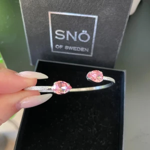 Silverarmband Caroline Svedbom - Jättefint armband från Caroline Svedbom i färgen light rose. Har tyvärr tappat bort orginal förpackningen så därför får man armbandet i denna ask som är på bilden. Armbandet är köpt i våras och är i mycket bra skick. Har släppt lite silverfärg på insidan av armbandet men syns inte när de sitter på (därav priset).