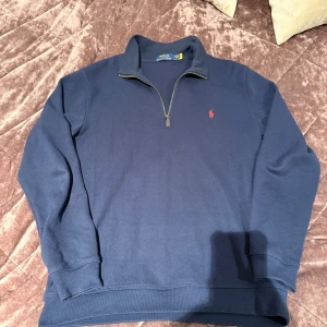 Mörk blå Polo Ralph Lauren Half-Zip - Säljer denna fina, stiliga mörkblåa polo Ralph lauren halt zip sweatshirt. Varan är i mycket bra skick, har varit använd några gånger, finns inga tecken på användning. Hör av dig vid intresse!
