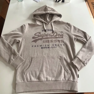 Beige Superdry hoodie - Säljer denna feta superdry hoodie i strl M. Den är i väldigt bra skick och har inga defekter. Perfekt till hösten och vintern. hör av er vid minsta funderingar!😁