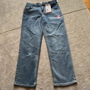 Aldrig använda: Levi's Loose Taper jeans blå stretch - Blå jeans från Levi's i modellen Loose Taper med stretch för extra komfort. Klassisk femficksdesign, normal midja och avsmalnande ben. Levi's Flex-teknologi ger extra rörlighet. Aldrig använda. Lappar kvar. 