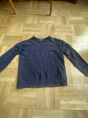Mörkblå tröja från Polo Ralph Lauren - Snygg mörkblå långärmad tröja från Polo Ralph Lauren. Mjuk insida och ribbade muddar vid ärmslut och nederkant. Perfekt för chill dagar och enkel att matcha med jeans.