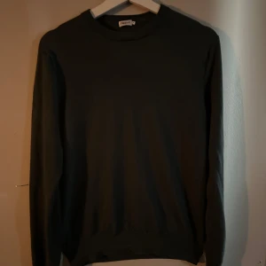 Mörk grön merinoull Filipa k - En stilren mörkgrön merinoull tröja från Filippa K i klassisk modell. Tröjan har rund halsringning och långa ärmar, perfekt för lager-på-lager eller som den är. Tillverkad i mjuk bomull för en skön känsla hela dagen.