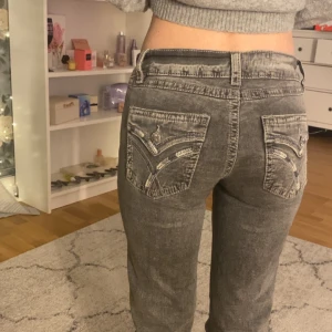 Grå bootcut jeans med broderade fickor - Snygga grå jeans med bootcut passform och låg midja. Jeansen har coola broderade detaljer. Är knappast andvända! Passar allt från 160-165 modellen på bilder är runt 158