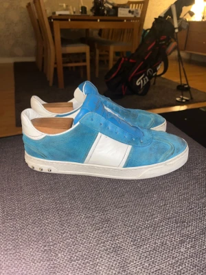 Valentino flycrew rockstud blå - !BYTER ENDAST! Väldigt bra pris förslag kan accepteras. (ALLA NITAR KVAR) ett par Valentino Rockstud sneakers i blå mocka och vitt skinn. Skorna har klassiska nitar på sulan, rund tå och snörning. Snygg kontrast mellan blått och vitt, perfekt för dig som vill sticka ut med exklusiva detaljer.