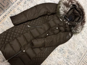 Rockandblue brun dunjacka med päls - Snygg brun dunjacka från Rockandblue med quiltade detaljer och fluffig päls på huvan. Jackan har flera dragkedjor, lång ärm och coolt emblem på armen. Perfekt för kalla dagar och har en riktigt schysst passform.