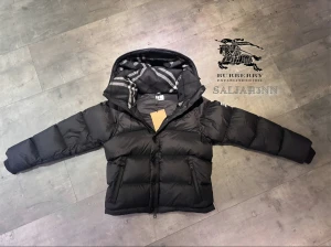 Burberry Puffer - Svart pufferjacka från Burberry med avtagbara ärmar så du kan bära den som väst. Jackan har huva med klassiskt rutigt Burberry-foder, dragkedja och knappar framtill samt snörning vid midjan. Fylld med dun och har praktiska fickor med dragkedja.