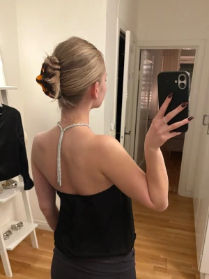 Svart halterneck topp med strassdetalj - En svart halterneck topp med glittrande strass runt halsen. Perfekt till nyårsafton/julfester! 