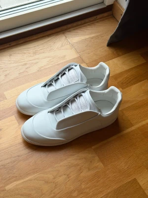 Maison Margiela - Enkla skor simpla men ändån inte. Vill du ha något som är stilrent fast ändån inte? Köpt då dessa futuristiska skorna. Som är från Maison Margiela! Skorna låter lite när man använder dock och går i dom! Kan vara för att de är i nästan helt nytt skick! Om du vill se fler bilder så får ni gärna säga till! Skorna låter lite när man går i dom pågrund av materialets friktion! Finns även en TikTok ute på dessa skorna! TikTok - ReLuxuria.