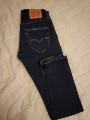 Levi's 520 mörkblå jeans - Snygga Levi's 511 jeans i mörkblå färg med klassisk femficksdesign och kontrastsömmar. Modellen är slim och har en rak, smal passform som sitter snyggt längs benen. Jeansen är tillverkade i slitstarkt denim och har den ikoniska Levi's-lappen bak i midjan.