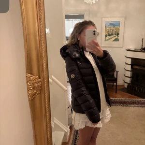 Svart pufferjacka från Moncler - Moncler dunjacka i bady modellen. Storlek 14 år. Alltså barn men identisk med storlek xs för kvinna. Sparsamt använd. Nypris 11000 kr. Kvitto finns!