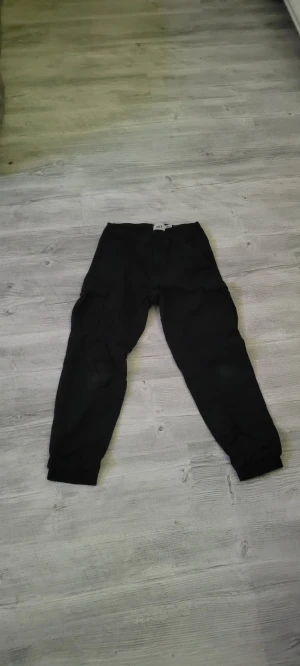 Svarta mjukisbyxor med resår - Svarta mjukisbyxor med resår vid bensluten och midjan. Byxorna har en avslappnad passform och är perfekta för chill dagar. Tillverkade i mjukt material som känns skönt mot huden. Snygga att matcha med hoodie eller t-shirt.