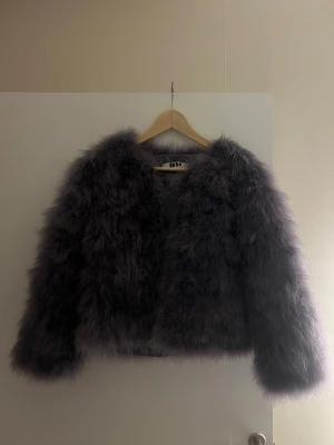 Mörkgrå fluffig pälsjacka från DM - Säljer en mörkgrå fluffig pälsjacka från DM med lång ärm och croppad passform. Jackan har en riktigt mjuk och voluminös look. 