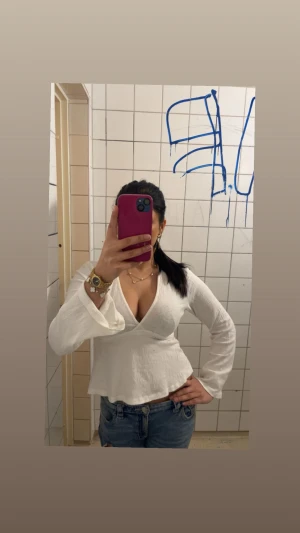 Vit blus med v-ringning från ginatricot  - Säljer en vit skit snygg blus med djup v-ringning från Ginatrocot och långa ärmar. Blusen tillverkad i ett tunt, strukturerat bomullstyg. Perfekt för dig som gillar en feminin och trendig stil sitter as bra perfekt för sommaren går å ha på sig den med nästan vad som helst 