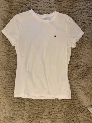 Tommy Hilfiger T-shirt  - Vit T-shirt från Tommy Hilfiger i storlek M men passar även S då den är liten i storleken. Endast använd 1 gång