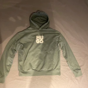 Grön hoodie från HUGO med tryck - Snygg grön hoodie från HUGO med vit logotyp på bröstet. Köpt för 1500kr på NK knappt använd 