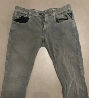 Replay Anbass Jeans - Snygga Replay Anbass jeans i en mörkgrå ton med klassisk femficksdesign och raka ben. Byxorna har diskreta Replay-loggor vid fickan och bakfickan. Materialet är mjukt och slitstarkt bomullsjeans, perfekt för dig som gillar stilrena och bekväma jeans.