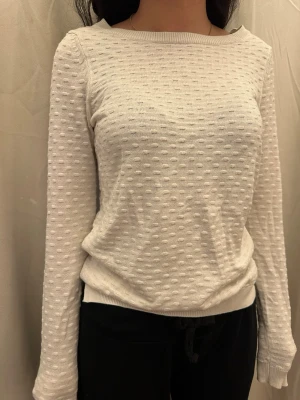 Vit prickig stickad tröja - Snygg vit stickad tröja med diskret prickigt mönster. Tröjan har långärmad design och rundad halsringning, perfekt för dig som gillar enkel men ändå unik stil. Mjuk och skön känsla som passar till jeans eller kjol.