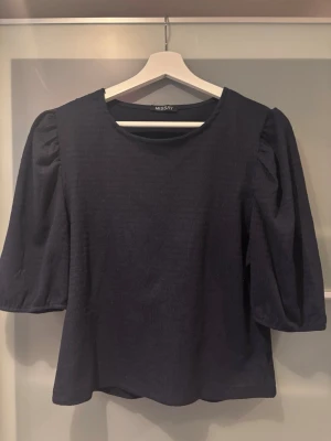 Mörkblå blus från Missay - Snygg mörkblå blus från Missay med rund halsringning och puffiga trekvartsärmar. Den är använd några gånger men är i gott skick!! 