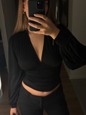 Svart omlott croppad topp - Säljer en svart topp från Nelly i storlek xs. Väldigt bra skick!