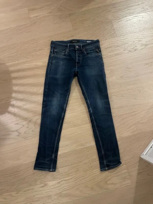Replay Willbi slim jeans blå, storlek 28/30 - Snygga mörkblå jeans från Replay, modell Willbi slim. De har klassisk femficksdesign, raka ben och diskreta slitningar för en cool look. Jeansen är i stretchigt denim och passar perfekt till en avslappnad stil.