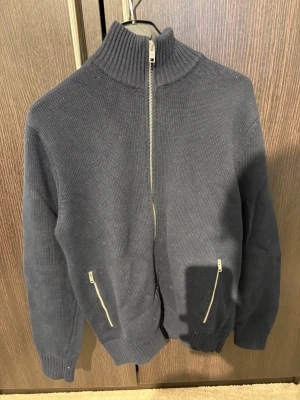 Mörkblå stickad kofta med dragkedja - Snygg mörkblå stickad kofta med hel dragkedja framtill och två fickor med dragkedja. Tröjan är från mango och i storlek S