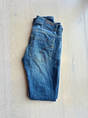 Dondup jeans - Snygga blå jeans från Dondup  med klassisk femficksdesign och raka ben. Jeansen har slitna detaljer och kontrastsömmar, samt en liten D-logga på bakfickan. Perfekta för en avslappnad och cool stil.