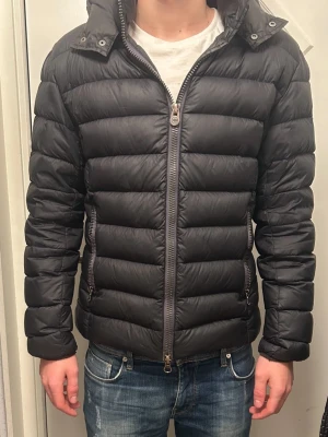 Colmar jacka  - Säljer en svart colmar jacka med huva och horisontella quiltade sektioner. Jackan har två fickor med dragkedja. Perfekt för kalla dagar och har en stilren look som funkar till jeans och sneakers. Pris kan diskuteras. Skriv vid minsta lilla intresse!🤩