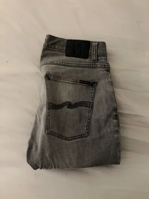 Gråa Nudie jeans  - Feta gråa nudie jeans med slitningar på knäna, storlek W34-L32 passar bra till varje outfit, slimfit passform.