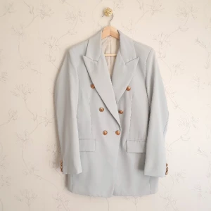 Ljusblå kavaj med brons knappar - 🦋FÖRST TILL KVARN!🦋 Himmelsblå kavaj med bronsknappar. Chic och passar bra när man vill piffa upp en basics outfit. Inte så använd av mig, köpt secondhand, säljer vidare, mycket god skick!🤍