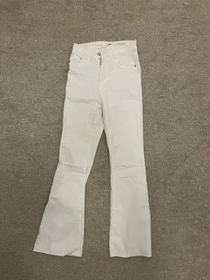VS Miss bootcut jeans - Snygga vita jeans från VS Miss i storlek 36. Modellen är bootcut med hög midja och klassiska fem fickor. Jeansen har dragkedja och knapp framtill samt bälteshällor. Perfekta för dig som gillar en clean och fräsch look.