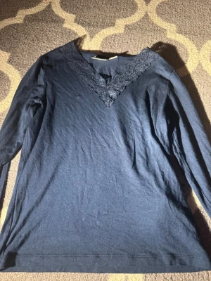 Marin blå långärmad topp med spets Gina Tricot - Marin blå långärmad topp från Gina Tricot med snygg v-ringning och spetsdetaljer längs halsen. Mjuk och skön, perfekt till jeans eller kjol. Enkel men ändå med en extra touch tack vare spetsen. Passar mig perfekt som bär storlek xxs-s i tröjor! Skriv ifall du har fler frågor eller funderingar, kan även lösa bilder med de på!💕😊