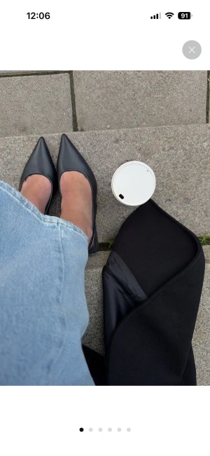 Klackar från NA-KD - Snygga svarta pumps från NA-KD med spetsig tå och smal klack. Skorna har en öppen häl med rem och är tillverkade i slätt skinnliknande material. Perfekta för dig som gillar stilrena och trendiga skor med en elegant siluett.