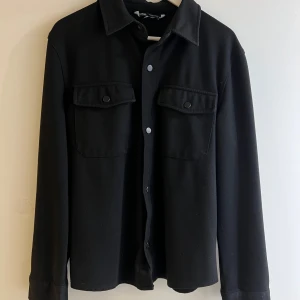 Svart overshirt från Zara - Stilren svart overshirt från Zara med klassisk krage och två stora bröstfickor med knappar. 👏👌🏼