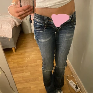 Blå bootcut jeans från Fornarina - Säljer ett par blå bootcut jeans från Fornarina med slitna detaljer och råa kanter. Jeansen har låg midja och snygga slitningar både fram och bak. Tyvärr är dragkedjan trasig, men eftersom de är så lågmidjade, så ser man inte det om man har på sig dem. Skriv gärna till mig om måtten då jag är osäker på storlek, eftersom den inte står! jag är 163 och måtten är W- 72cm L-82cm, passar förövrigt mig bra i längden! gylfen är trasig, men syns knappt med byxorna på (se bild)