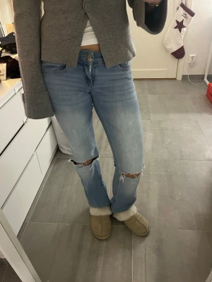 Bootcut ljusblå jeans med slitningar - Snygga ljusblå bootcut jeans med hål på knäna från Nelly. Lite slitna längst ner på ena benet men inget man tänker på, sedan även slitna på rumpan vid fickorna. Sedan har jag sytt vid en av grejerna där man kan ha ett skärp då den lossnat, se detta på sista bilden, kan skicka bättre bild också om de önskas💕