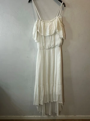 Vit långklänning från Kappahl - Superfin vit långklänning från Kappahl med smala axelband och volang upptill. Klänningen har broderade detaljer på volangen och är tillverkad i ett lätt, luftigt material. Perfekt för sommarens alla tillfällen!