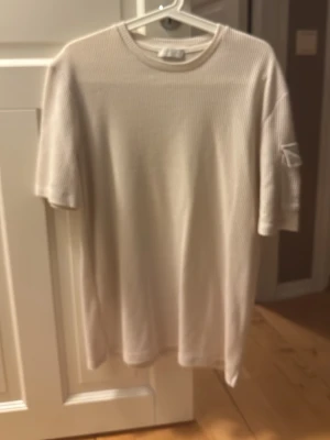 Ribbad beige t-shirt med kort ärm - Säljer en ribbad beige t-shirt med korta ärmar och rund hals. T-shirten har en clean och enkel look med diskreta ränder i materialet. Perfekt för dig som gillar stilrena och neutrala plagg. Materialet känns mjukt och skönt mot huden.