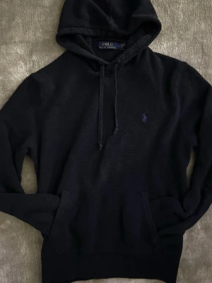 Ralph lauren hoodie - En mörkblå Ralph lauren stickad hoodie är ute‼️‼️Skick 8/10✅✅ Kontakta vid minsta fundering🤗🤗                                                               Polo ralph lauren stickad hoodie mörkblå M marinblå pike puffer Helmut Lang kashmir ull pima vinter cardigan Moncler