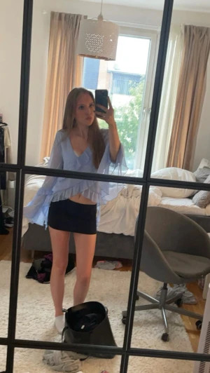 Ljusblå blus från Bik Bok - Supersöt ljusblå omlottblus från Bik Bok med v-ringning och breda ärmar. Blusen har volangdetaljer längs halsringningen och framtill, perfekt för vår och sommar. 