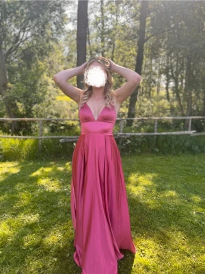 Balklänning med fickor - Säljer min balklänning, endast använd en gång💕Elegant, bekväm rosa långklänning med djup v-ringning, tunna axelband och FICKOR! Köpt på JJhouse för 1445kr + frakt på 330kr, färgen heter ”kanelros” på hemsidan. Perfekt för bal eller andra tillställningar! Sitter snyggt i midjan och har ett svepande fall. Uppsydd hemma. Kan även skicka med sytråd som matchar klänningen🥰