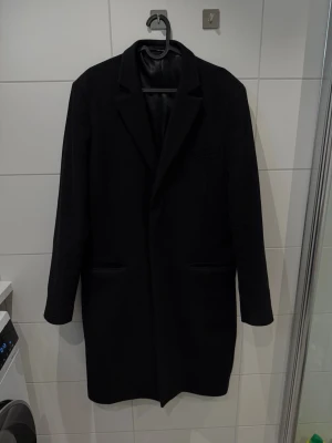 J.Lindeberg ullrock med snygg passform - strl 52/L - Svart ullrock från J.Lindeberg med klassisk krage och snyggt skräddad passform. Jackan har tre knappar framtill, två sidofickor och en bröstficka. Perfekt för dig som gillar stilrena och tidlösa plagg.