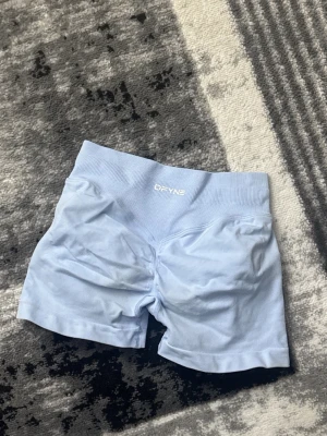 Ljusblå seamless shorts från dfyne  - Säljer ett par ljusblå seamless shorts från dfyne med hög midja och ribbad linning. Perfekta för träning eller chill dagar. Materialet är mjukt och stretchigt syntet som sitter skönt mot kroppen.