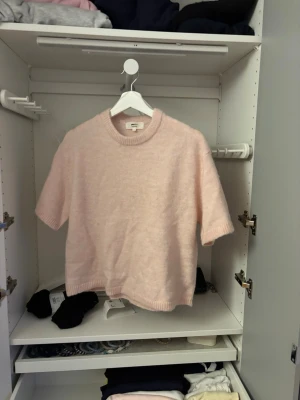 Ljusrosa stickad topp  - Mysig ljusrosa stickad topp från Gina tricot med korta ärmar och rund hals. Toppen har ribbade kanter vid hals, ärmslut och nederkant.