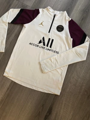 Psg X Jordan tränings tröja 21/22  - PSG x Jordan långärmad träningströja – EXKLUSIV  Riktigt snygg och eftertraktad PSG x Jordan långärmad tröja. Stilren vit design med vinröda detaljer och halv zip som ger en premium look. Bekvämt material med perfekt passform – funkar lika bra till träning som till vardags. PSG-märket och Jordan-loggan gör den både sportig och exklusiv.  Svår att hitta – perfekt för dig som vill sticka ut 💎  Skick: Mycket bra Passform: Normal 