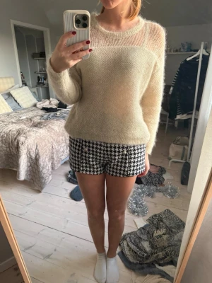 Svarta och vita rutiga shorts med knappar - Säljer ett par snygga shorts med svartvitt hundtandsmönster och sex dekorativa guldfärgade knappar framtill. 