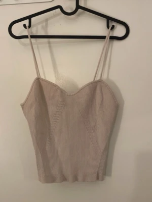 Beige ribbad linnetopp från H&M - Säljer en beige ribbad linnetopp från H&M i storlek M. Toppen har smala axelband och en snygg sweetheart-ringning. Materialet är mjukt och stretchigt. Enkel och stilren design som är lätt att matcha med olika outfits.