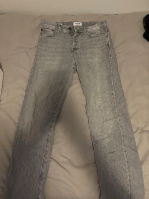 Grå jeans Relaxed Chris Jack & Jones - Säljer ett par grå jeans från Jack & Jones, modellen Relaxed Chris. De har en avslappnad passform med raka ben och klassisk femficksdesign. Jeansen är tillverkade i bomull och har en snygg, ljusgrå tvätt som ger en cool vibe.