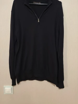 Marinblå zip tröja Oscar Jacobson - Marinblå långärmad kashmir tröja från Oscar Jacobson med half zip framtill. Tillverkad i Italien, stilren och enkel design med ribbade muddar vid ärmslut och hals. Helt ny! Köpt för 2499