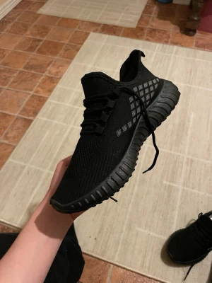 Svarta sneakers med stickad ovandel - PRISET KAN SÄNKAS, SKRIV OM DET BEHÖVS Säljer ett par svarta sneakers med stickad ovandel och coola rutiga detaljer på sidorna. Skorna har snörning och en rejäl, räfflad sula för extra grepp. Perfekta för dig som gillar sportig och modern stil.